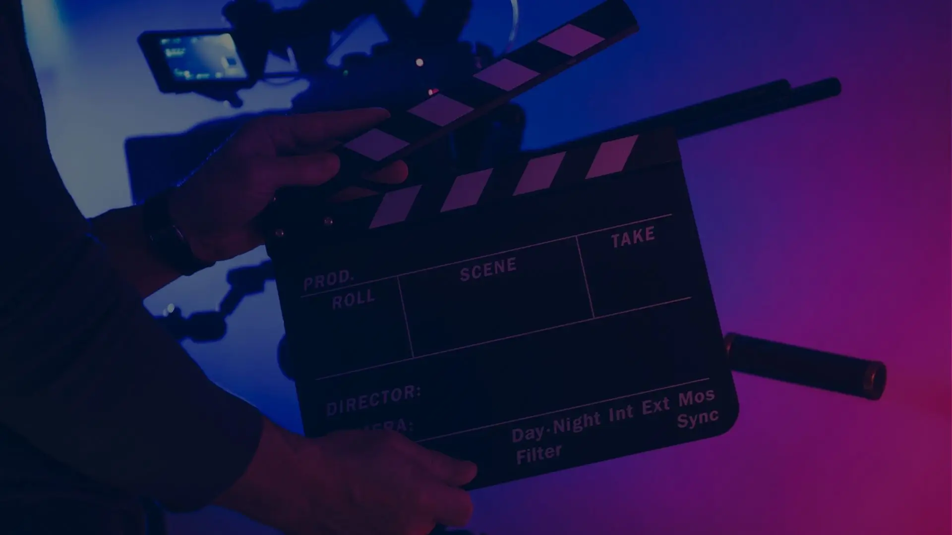 Film slate in a dark recording studio with blue and purple accent lighting, representing cinematic audio post production.